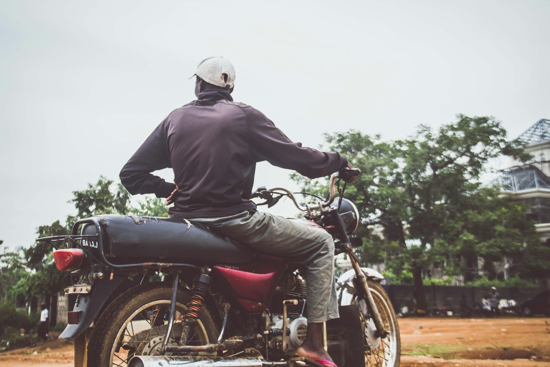 A dispatch rider on a motorcycle on a tree-lined road